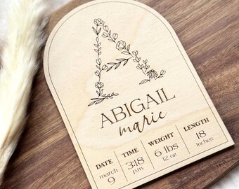 Könnte beinhalten: Holz-Geburtsanzeigetafel mit gewölbtem Oberteil. Der Name "ABIGAIL marie" wird zusammen mit Geburtsdaten angezeigt: Datum, Uhrzeit, Gewicht (2,95 kg) und Länge (45,7 cm). Der Buchstabe "A" ist mit floralen Elementen verziert.