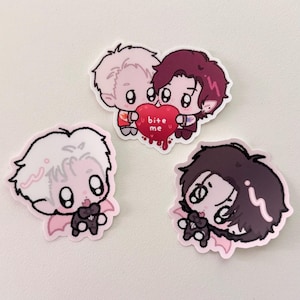May include: Three cartoon stickers featuring chibi vampire characters. One sticker shows two characters holding a heart with the text "bite me." The other two stickers show individual characters with bat wings and bow ties. The stickers have a pink outline.