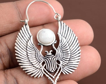 Puede incluir: Pendientes de aro plateados con un diseño detallado de escarabajo alado. Cada pendiente tiene una piedra blanca central. Las alas están intrincadamente detalladas y el diseño general tiene un acabado antiguo. Joyería única.