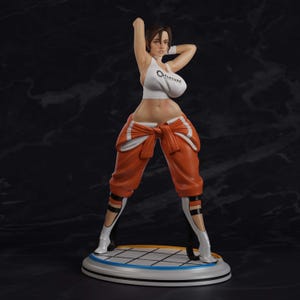 May include: A collectible figurine of a character with brown hair, wearing a white tank top with the Aperture Science logo, orange pants tied at the waist, and white boots. The figure stands on a circular base with a white and black grid pattern.