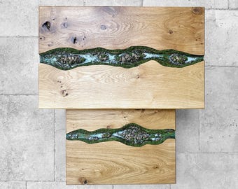 May include: Two wooden tables with a river design. The tables are made of light-colored wood with a river of green and blue epoxy resin and stones running through the center. The tables are rectangular.