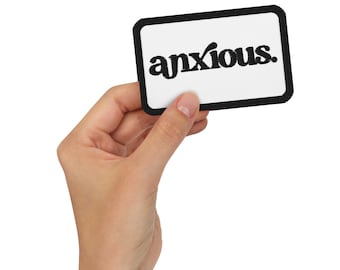 May include: A white card with a black border and the word "anxious" printed in black.
