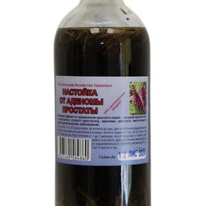 Puede incluir: Una botella de vidrio transparente con tapa plateada, llena de líquido oscuro y materia vegetal. La etiqueta presenta texto cirílico y una ilustración floral. La botella contiene 250 ml.
