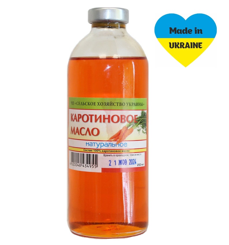 Puede incluir: Una botella de vidrio de aceite de zanahoria de color naranja con una etiqueta blanca que dice "Каротиновое Масло натуральное" (Aceite de zanahoria natural) y una fecha de caducidad de "21 ЖОВ 2024". La botella est&aacute; etiquetada con "Made in UKRAINE" con un coraz&oacute;n amarillo y azul.