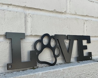 May include: Black metal wall decor with the word "LOVE" and a paw print in the center.