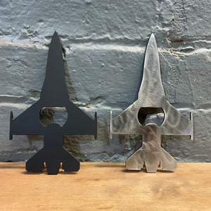 May include: Two metal bottle openers shaped like F-16 fighter jets. One is black and the other is silver.