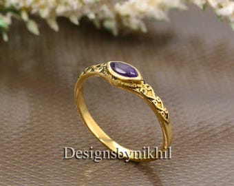 May include: A gold ring with an intricate design and a purple gemstone.