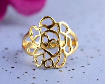 Puede incluir: Un anillo de color dorado con un diseño delicado e intrincado que se asemeja a una flor. El anillo está hecho de metal y tiene un patrón de filigrana.