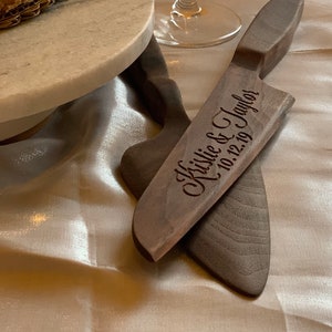 Puede incluir: Un cuchillo para pastel de madera con el texto "Kistlie & Taylor 10.12.19" grabado en él.