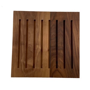Op de afbeelding: Een houten paneel met verticale groeven, met twee verschillende soorten hout. De linkerkant is een lichter hout met een roodachtige tint, terwijl de rechterkant een donkerder hout is met een bruine tint.