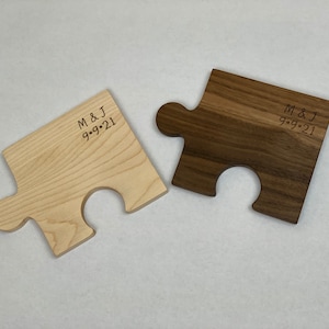 Könnte beinhalten: Zwei Holzsägeblatt-Puzzleteile, eines aus hellem Holz und eines aus dunklem Holz, mit dem Text "M & J 9-9-21" auf jedem Teil graviert.
