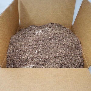 May include: A cardboard box filled with brown shredded paper. The box is open, revealing the contents inside. The shredded paper appears to be a packing material.