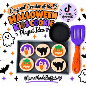 May include: A Halloween-themed kids' cookie playset featuring a gray rectangular tray with six round wooden cookies decorated with ghost, cat, and pumpkin designs. Includes a black toy pan and a purple and orange spatula with a pumpkin icon.