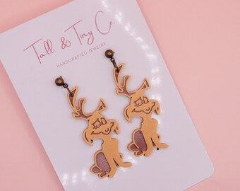 Può includere: Un paio di orecchini pendenti con un design a personaggio dei cartoni animati. Gli orecchini sono marrone chiaro con un contorno marrone più scuro e un interno rosa-viola. Sono su una carta bianca con il testo "Tall & Tiny Co."