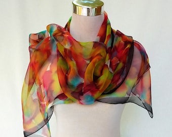 Op de afbeelding: Een kleurrijke zijden sjaal met abstracte bloemenpatronen in tinten rood, oranje, geel, groen en blauw. De sjaal is gedrapeerd over een wit mannequin.