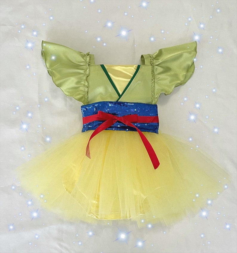May include: A yellow tulle tutu with a green satin bodice and blue and red sequined belt. The bodice has a V-neck and short, ruffled sleeves.