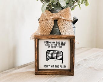 Orinar en el asiento es como golpear el poste con la portería vacía, humor de baño, baño de hockey, regalo con temática deportiva, letrero de baño, baño de niños