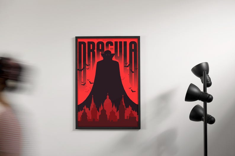 May include: A black framed poster with a red background and a silhouette of Dracula in a cape. The poster says "Dracula" in large, bold letters.