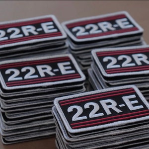 May include: A stack of black and white embroidered patches with red stitching. The patches read "22R-E".