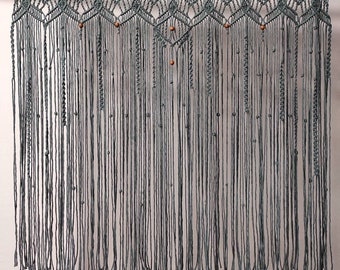 May include: A gray macrame wall hanging with wooden beads. The hanging has a geometric pattern and is made of thick yarn.