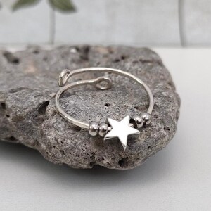 May include: A silver adjustable ring with a star charm and small silver beads.