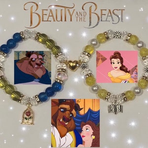 May include: Two beaded bracelets with charms. One bracelet is blue and yellow with a charm of a rose in a glass dome. The other bracelet is yellow with a charm of an open book. The bracelets are displayed on a white background with the text "Beauty and the Beast".