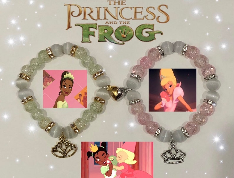 May include: Two beaded bracelets with charms. One bracelet is white with green glitter and a gold lotus flower charm. The other bracelet is white with pink glitter and a silver crown charm. The bracelets are inspired by the Disney movie "The Princess and the Frog".