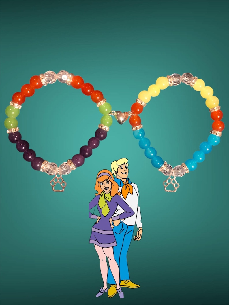 May include: Two rainbow-colored beaded bracelets with silver charms, connected by a silver heart charm. The bracelets are in the shape of an infinity symbol. The bracelets are in front of a cartoon image of a man and woman.