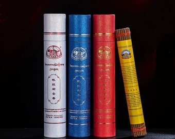 Peut inclure: Trois boîtes en carton blanc, bleu et rouge avec des inscriptions dorées et un motif doré. Les boîtes contiennent des bâtonnets d'encens. Les bâtonnets d'encens sont jaunes avec des inscriptions dorées et un motif doré. Les boîtes sont étiquetées "Zangdok"
