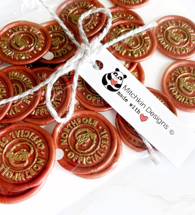 May include: A package of 20 gold and red wax seals with the text "North Pole Official Seal" and a cartoon image of Santa Claus. The package is tied with twine and a white tag with a panda bear illustration and the text "Mitchkin Designs made with love".