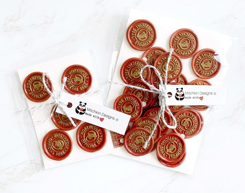May include: A set of 20 red wax seals with gold lettering. The seals say "North Pole Official Seal". The seals are packaged in two clear plastic bags with white labels that say "Mitchkin Designs made with ❤️".