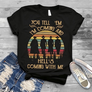 May include: Black t-shirt with a retro sunset graphic and the text "You tell 'em I'm coming and hell's coming with me".