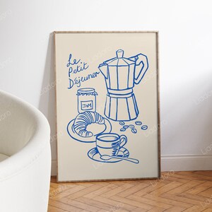 May include: A framed illustration of a French breakfast scene with blue line drawings of a coffee pot, a croissant, a jar of jam, a cup of coffee, and coffee beans. The text "Le Petit D&eacute;jeuner" is written in blue cursive.