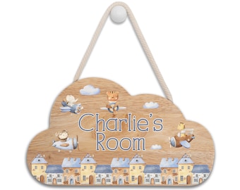 May include: A wooden cloud-shaped door sign with a blue and yellow town scene at the bottom. The sign has a rope for hanging and says "Charlie's Room" in blue lettering. There are three animals flying in airplanes above the town.