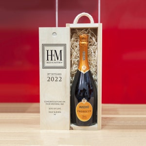 May include: A wooden gift box with a bottle of Maschio Prosecco inside. The box is personalized with the initials "HM" and the names "Helen & Matthew". The date "28th September 2022" is also printed on the box. The message "Congratulations on your wedding day. Lots of love, Sally & John xx" is printed on the box.