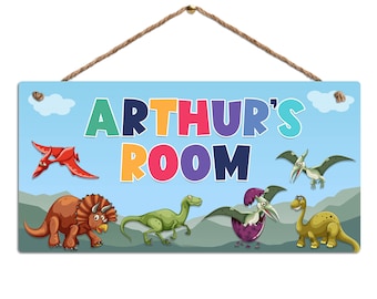 May include: A blue wooden sign with the text "ARTHUR'S ROOM" in colorful letters. The sign is decorated with dinosaurs, including a pterodactyl, a triceratops, and a velociraptor.