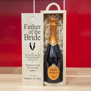 Puede incluir: Caja de regalo de madera con una botella de prosecco en su interior. La caja está grabada con el texto "Father of the Bride", un gráfico de esmoquin, la fecha "7th September 2019" y el mensaje "Thank you for all your love and support. Love from Matthew & Chloe".