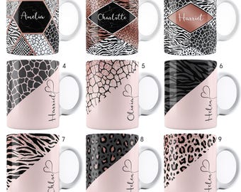 May include: Nine different designs of ceramic mugs with a pink and black animal print design. Each mug has a different name written on the pink portion of the mug. The names are Amelia, Charlotte, Harriet, Olivia, Helen, and Chloe.