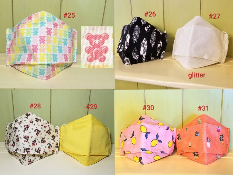 K&ouml;nnte beinhalten: Zehn verschiedene Stoffmasken mit verschiedenen Mustern, darunter Teddyb&auml;ren, Federn, Zitronen und Blumen. Die Masken sind von 25 bis 31 nummeriert.