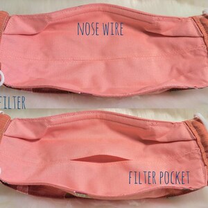 K&ouml;nnte beinhalten: Eine rosa Stoffmaske mit einem Fach f&uuml;r einen Filter und einem Nasendraht. Der Text "FREE FILTER" und "FILTER POCKET" ist auf der Maske aufgedruckt.