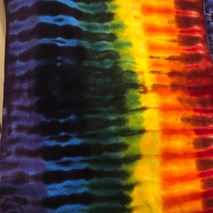 May include: A tie-dye textile with a vibrant spectrum of colors. The design features vertical stripes of blue, green, yellow, orange, and red, creating a visually striking and artistic pattern. The fabric has a soft, textured appearance.