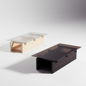 Puede incluir: Dos mesas de centro rectangulares con tapas de cristal. Una es de madera clara con tapa de cristal transparente, la otra es de madera oscura con tapa de cristal oscuro texturizado. Las mesas tienen un diseño moderno y minimalista.