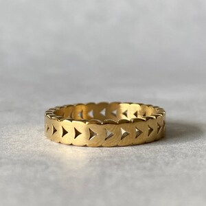 Könnte beinhalten: Ein goldfarbener Ring mit geometrischem Design. Der Ring besteht aus einer Reihe verbundener Dreiecke.