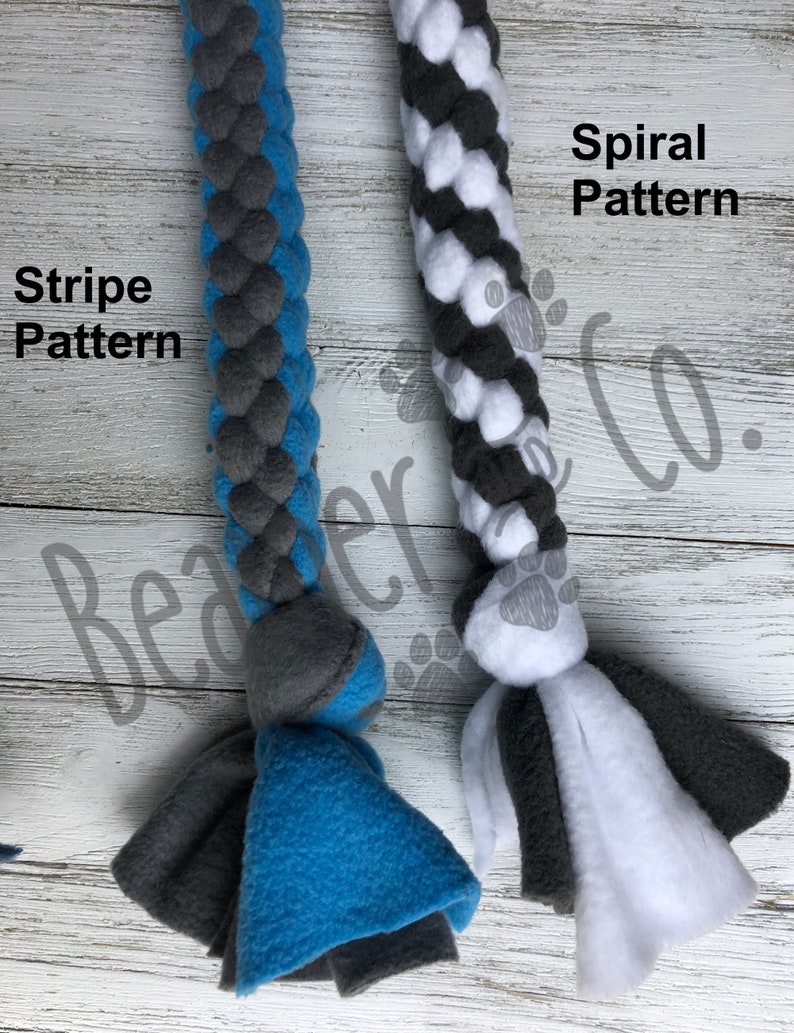 May include: Two dog toys with braided rope designs. One is blue and gray with "Stripe Pattern" text, and the other is white, gray, and black with "Spiral Pattern" text. Both have fleece tassels at the ends.