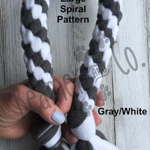 May include: A gray and white dog toy with a large spiral pattern. The toy is made of soft fabric and has a braided design. The text "Large Spiral Pattern" and "Gray/White" are visible.