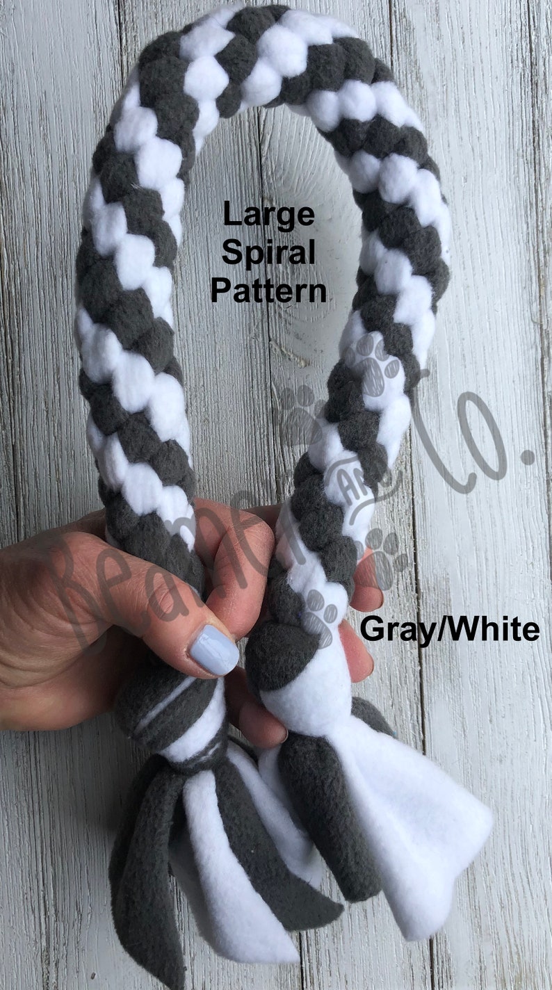 May include: A gray and white dog toy with a large spiral pattern. The toy is made of soft fabric and has a braided design. The text "Large Spiral Pattern" and "Gray/White" are visible.