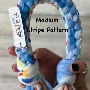 May include: A blue and white dog toy with a medium stripe pattern. The toy is made of soft fabric and has a tie-dye design with blue, orange, and yellow accents. The tag reads "Beamer & Co."