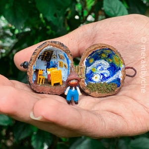 May include: A miniature figurine of a person standing in front of a walnut shell painted to look like a room. The other half of the walnut shell is painted with a starry night scene.