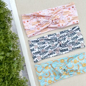 May include: Three colorful headbands with different patterns. The first headband is pink with a white pattern of medical symbols and the text "Medical Assistant". The second headband is white with a black pattern of flowers and the text "Medical". The third headband is light blue with a white pattern of rainbows, smiley faces, and stethoscopes.