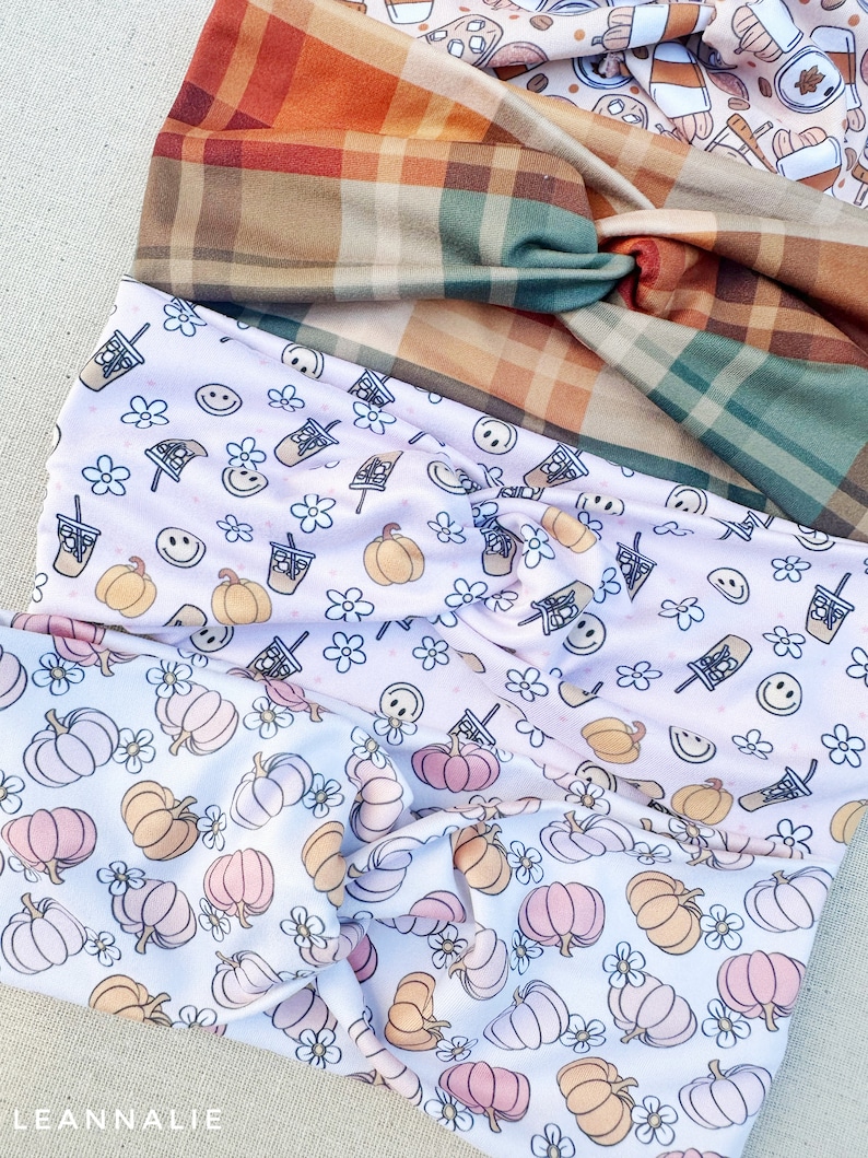 May include: Three fabric headbands with different patterns. The top headband is a plaid pattern in shades of brown, green, and orange. The middle headband is a white fabric with a pink and orange pumpkin and flower pattern. The bottom headband is a white fabric with a pink and orange pumpkin and flower pattern.